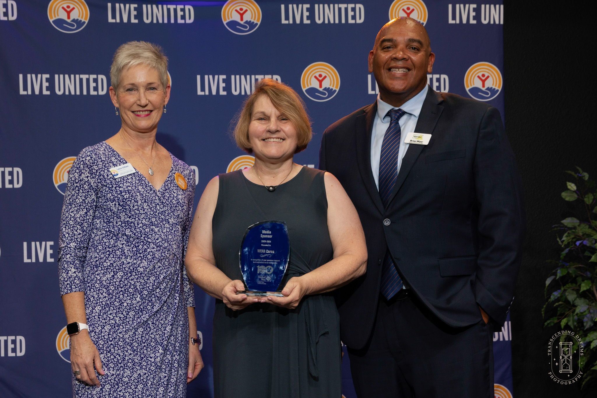 Brian Wyer, Kathy, and Laura, with award thanking WEAR for their media partnership for 2023-2024